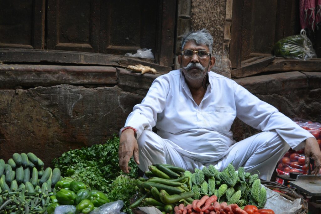 A local vegetable seller sits amongst fresh produce in Old Delhi market, India.